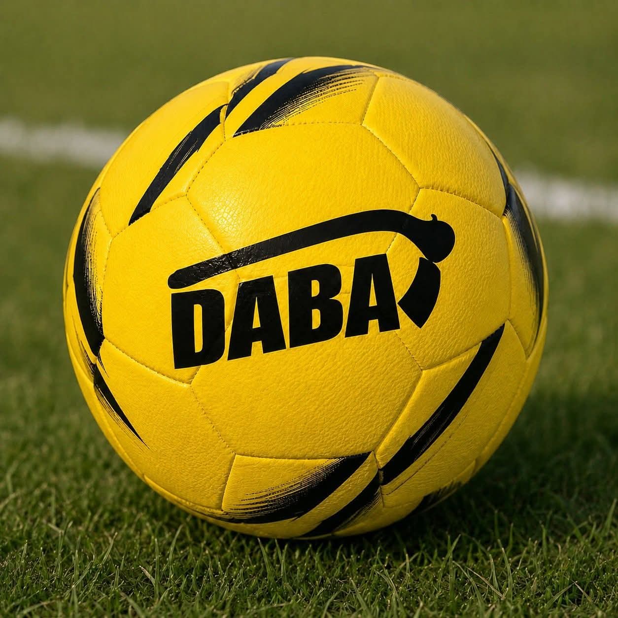 Ballon de football DABA jaune et noir posé sur une pelouse de stade